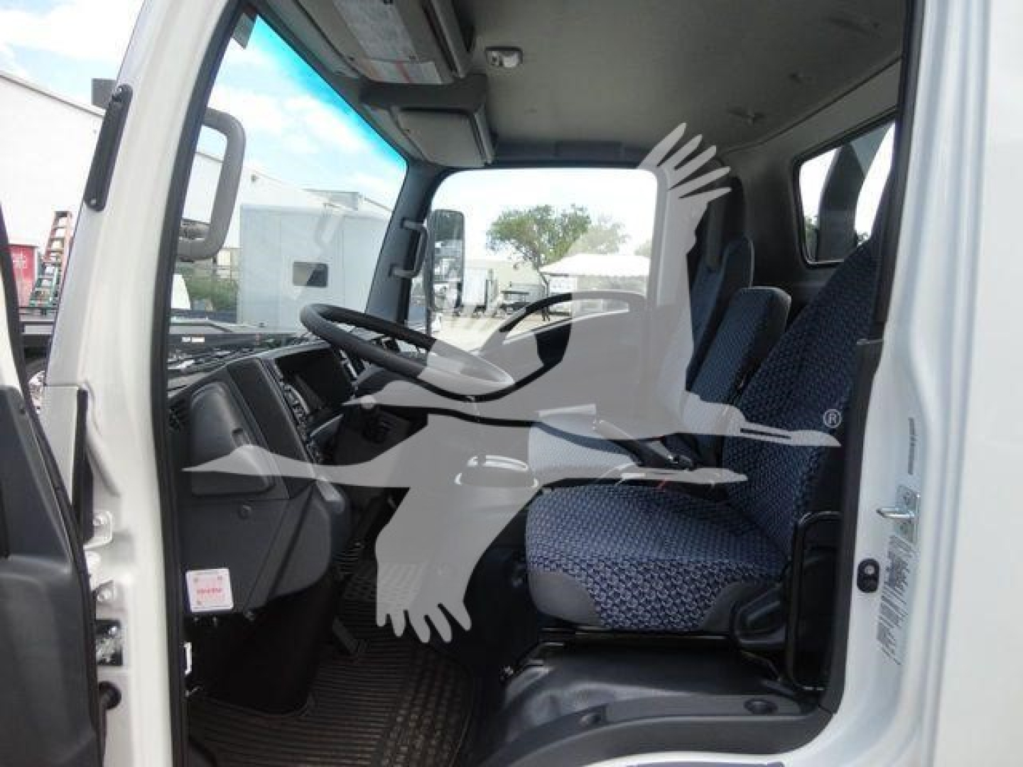 Isuzu NRR cab interior showing driver seat and steering wheel with dashboard and passenger seat.
