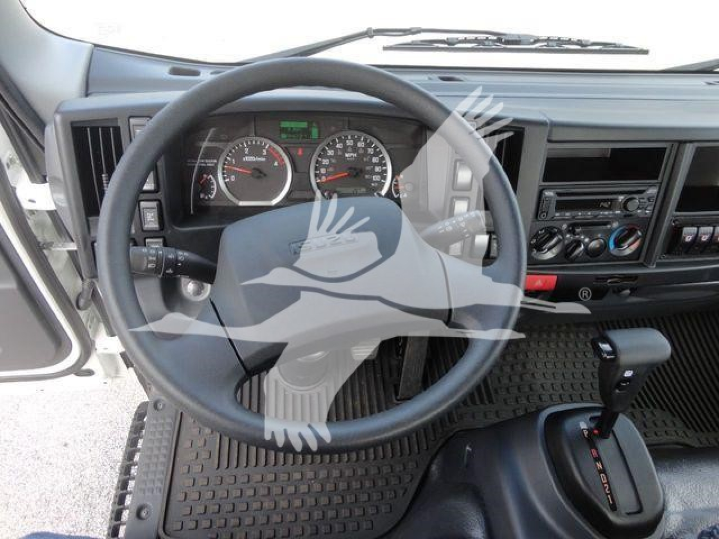 Isuzu NPRR dashboard view showing steering wheel, gauges, and center console of cab with gear shifter visible