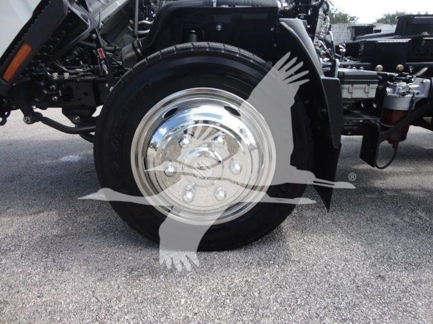 Isuzu NPR truck front wheel and chrome hubcap in view showing wheel and suspension components