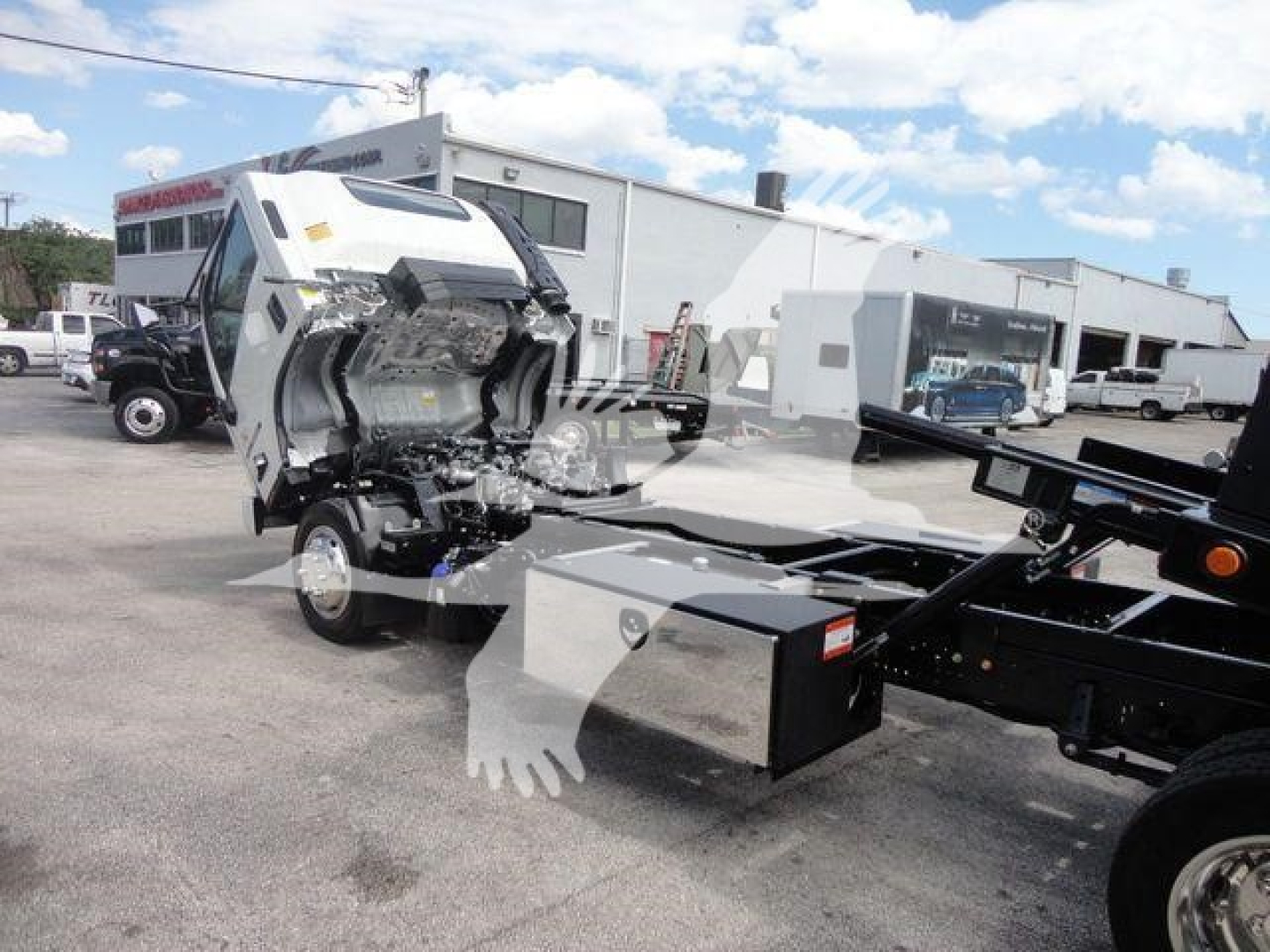 Isuzu NPR rollback truck cab/chassis with punch-drawn diesel engine bay exposed, front view showing mechanical components and flatbed frame.