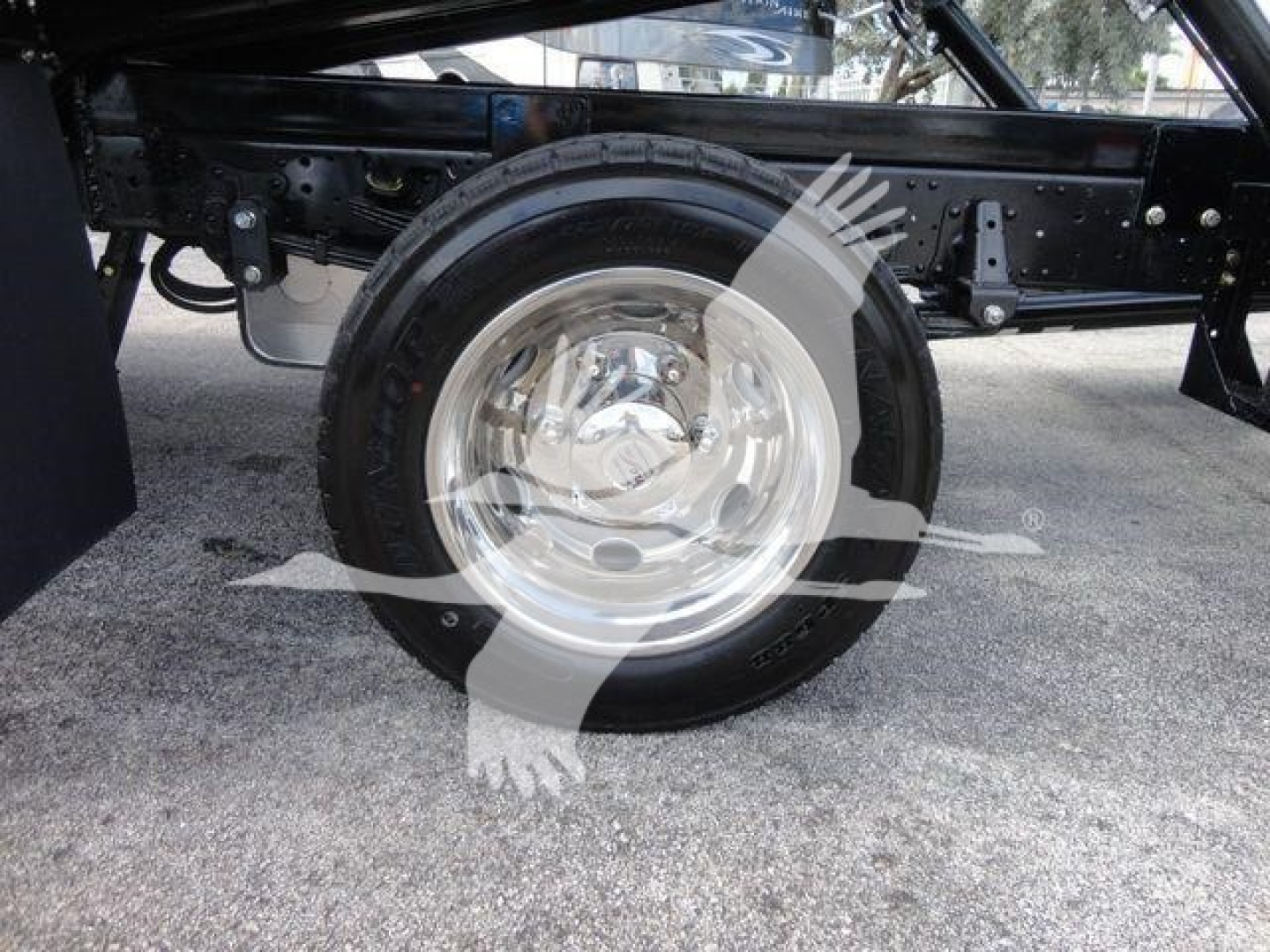 Isuzu NPR-? wheel area showing aluminum rim and tire, undercarriage with frame rails and suspension components.