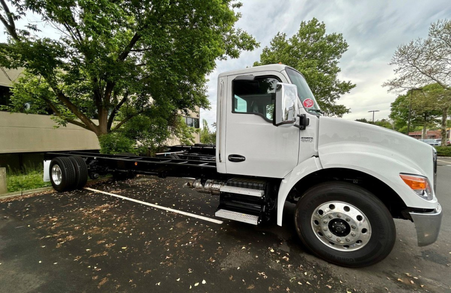 Kenworth T280 chassis cab in an empty lot, side view showing cab and bare frame with no cargo box, VIN plate not visible, stock U1037.