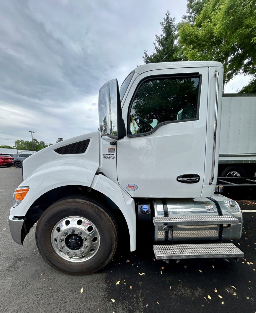Kenworth T280 regional tractor cab side view showing chrome fuel tank and steps, front wheel, and part of refrigerated trailer connection.