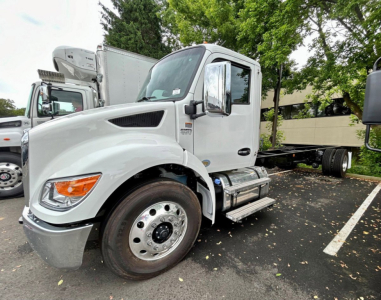 Kenworth T280 cab in white parked, front-left view, with chrome mirrors, large front wheel, and reefer truck chassis visible.