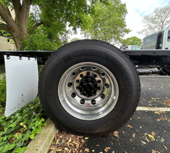 Truck wheel assembly with Continental tire and shiny aluminum rim; part of a Kenworth T280 chassis visible.