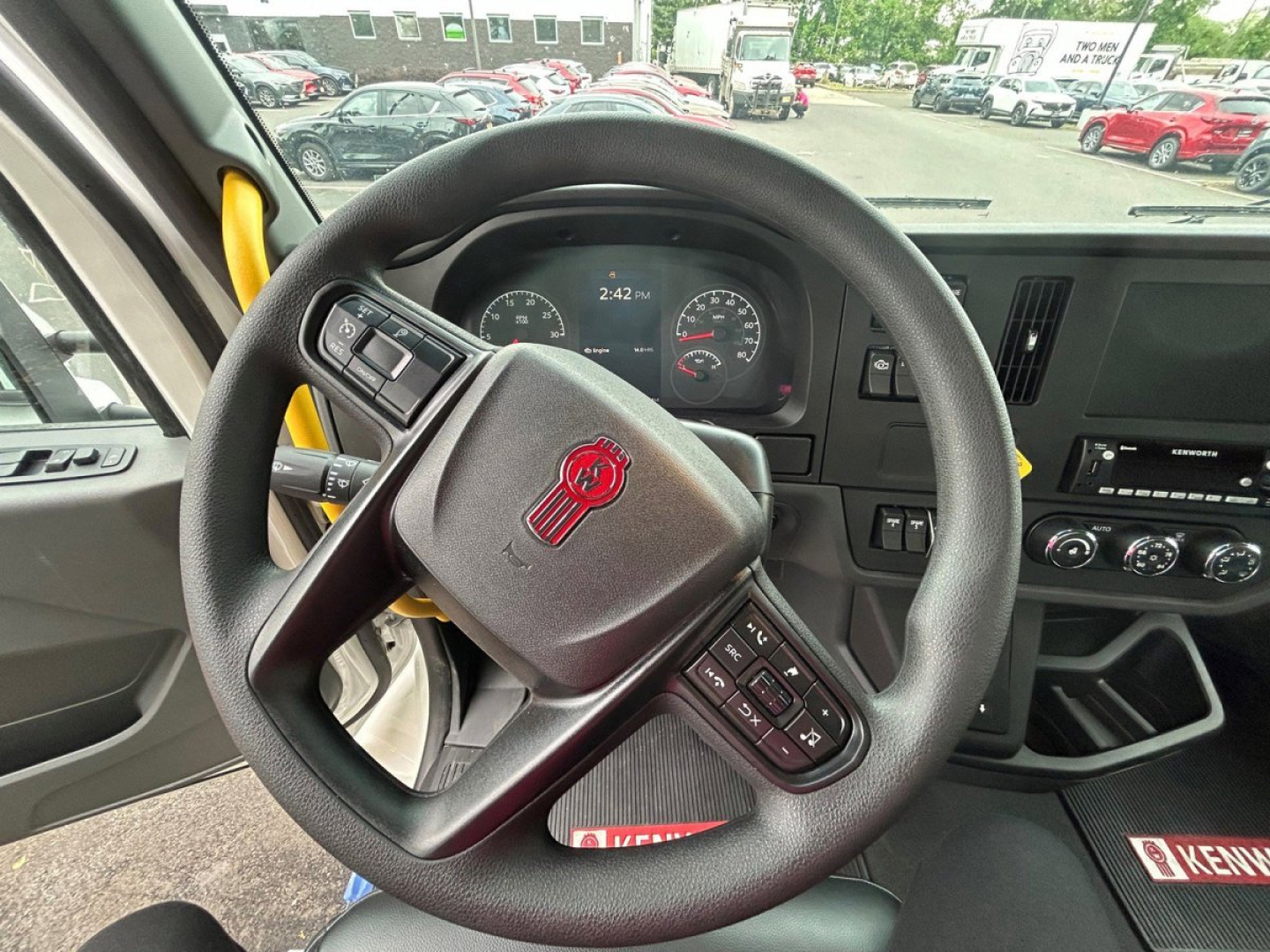 Steering wheel and instrument cluster of a 2025 Kenworth T280 cab interior showing dashboard controls and steering wheel with Kenworth emblem.