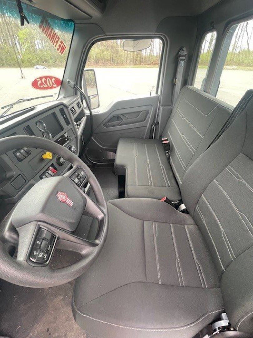 Kenworth T280 cab interior showing driver seat, steering wheel, and front passenger seat; dashboard with controls and windows visible.