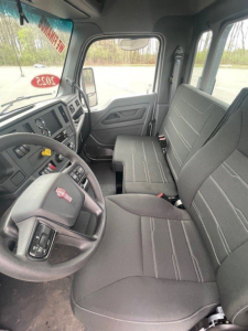 Kenworth T280 cab interior showing driver seat, steering wheel, and front passenger seat; dashboard with controls and windows visible.