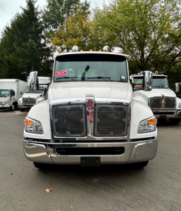 Front view of a white 2025 Kenworth T280 tow truck showing grille, chrome bumper, and headlights.
