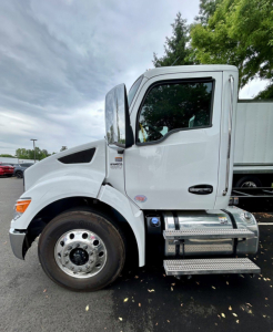 Kenworth T280 tow truck side view showing cab and wheels with chrome fuel tank and steps.
