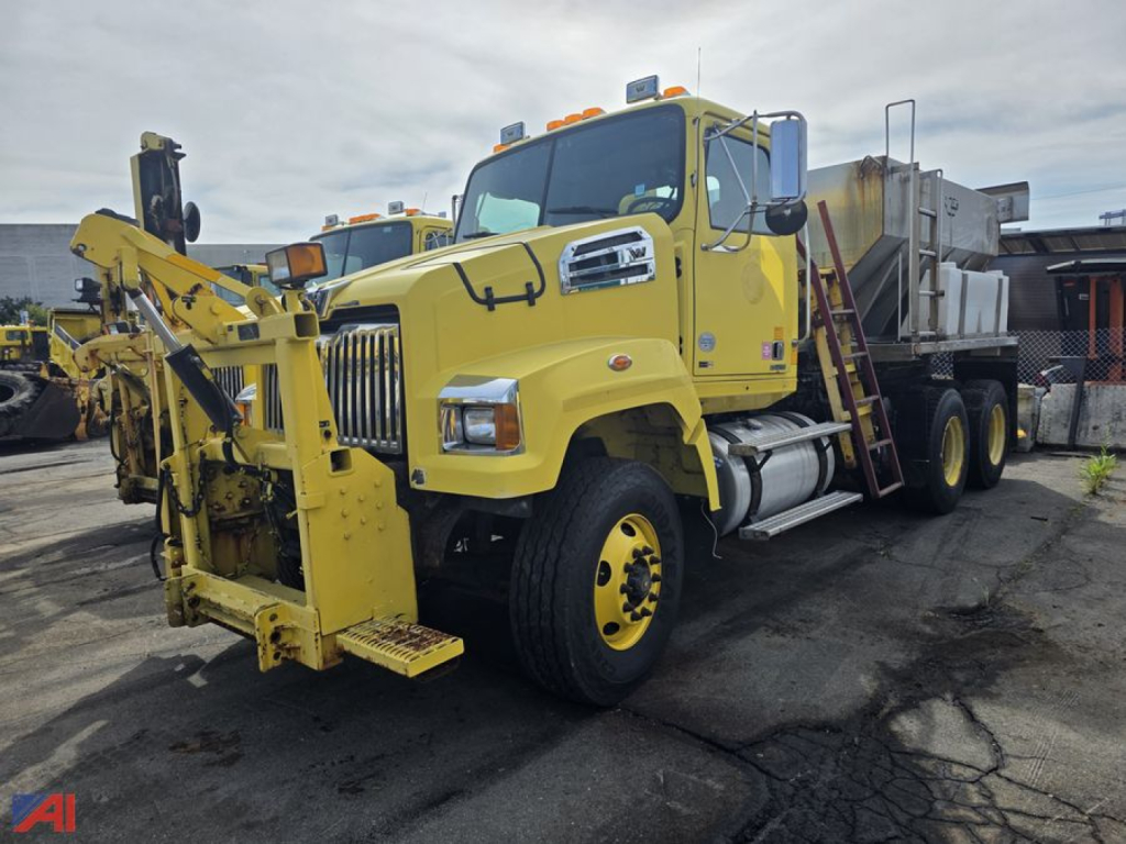 Yellow Western Star 4700 stone spreader truck with front mounted attachment and large tires, VIN label visible, side steps and cab mirror