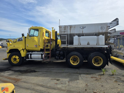 Image of a yellow Western Star 4700 cement or stone spreader truck with a large hopper on the back and dual rear axles.