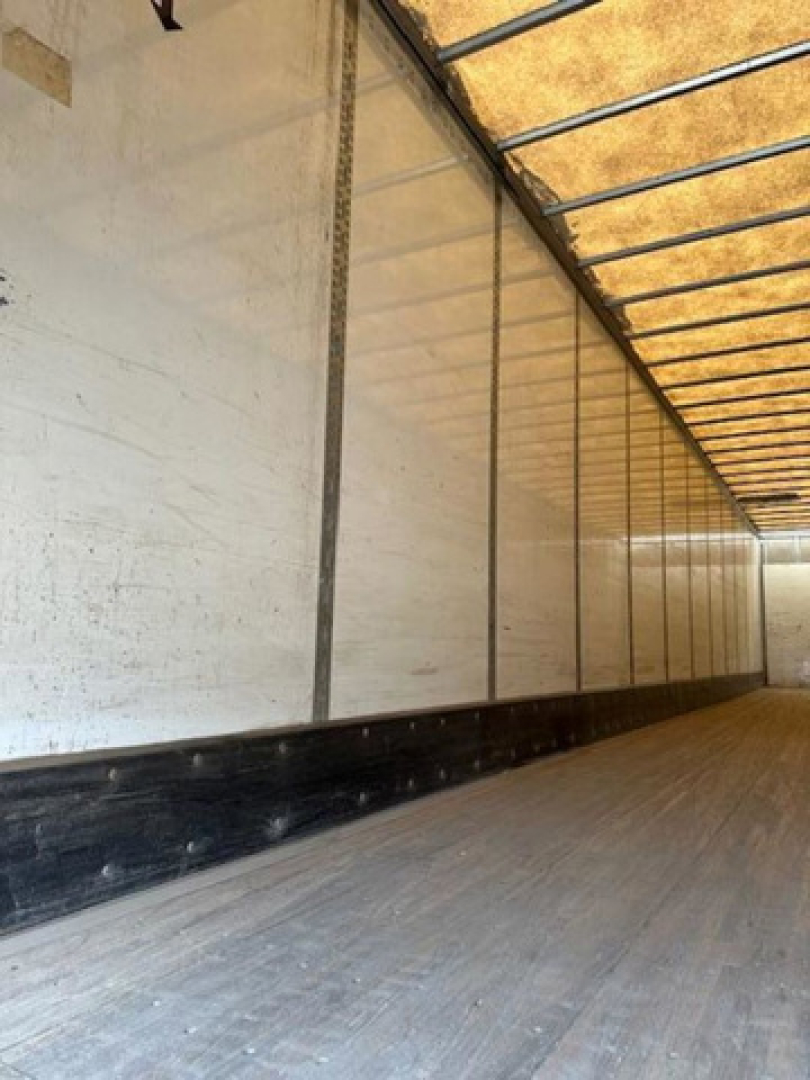 Trailer interior showing wooden floor and white sidewalls with a black lower trim.