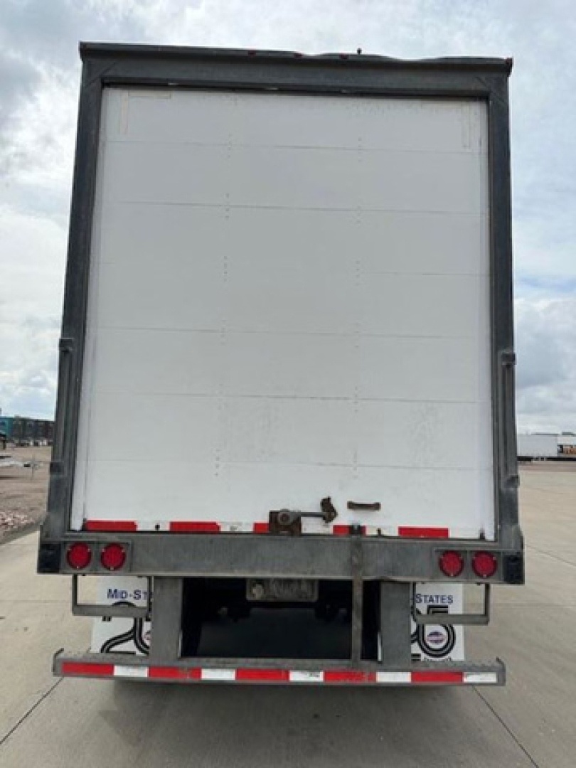 Rear of a white Wabash van trailer showing rear doors and bumper with taillights. No legible serials or text visible on the doors in the image.