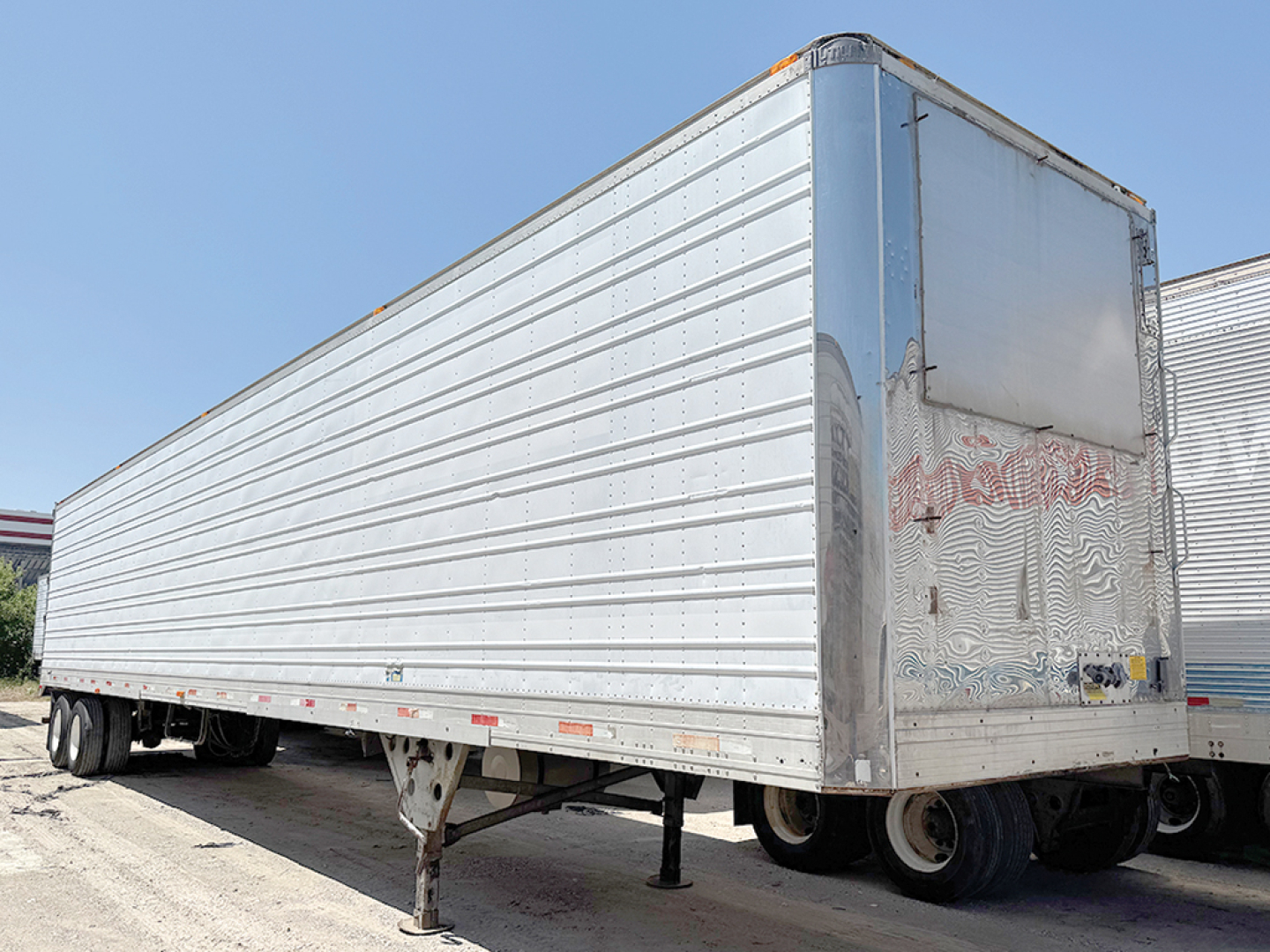 Trailer side view of a 1998 aluminum reefer with raised ribbed panels and front door, stock 553186.