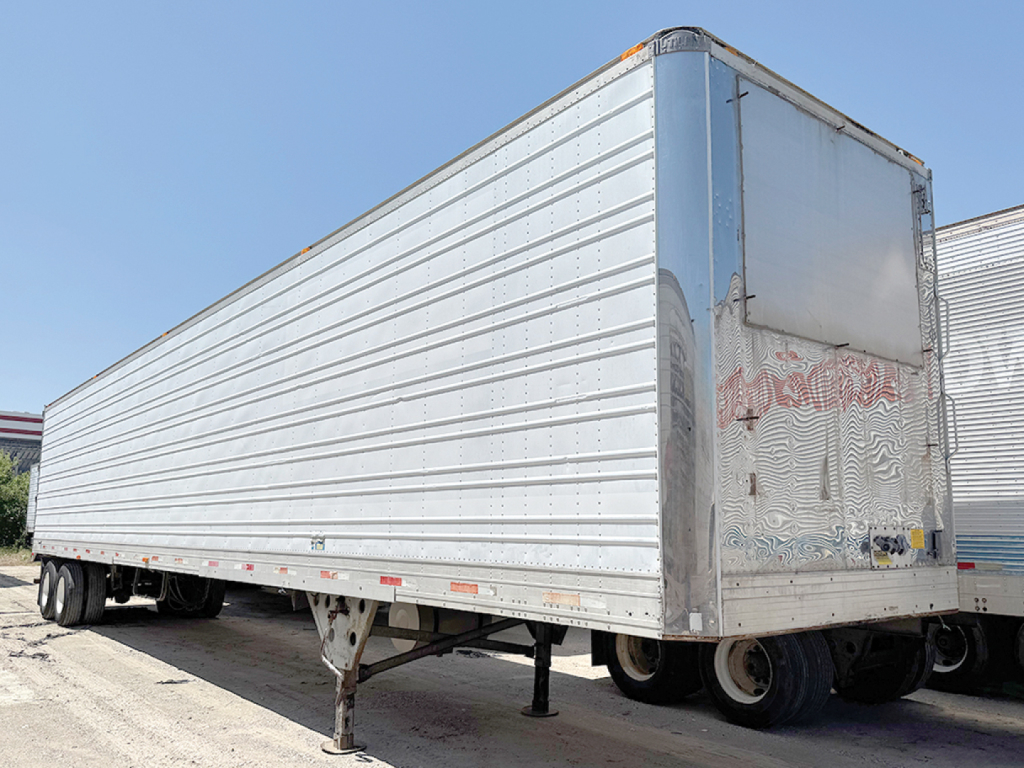 Trailer side view of a 1998 aluminum reefer with raised ribbed panels and front door, stock 553186.