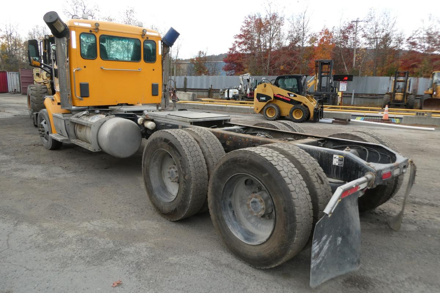 Peterbilt 567 cab tractor presenting a yellow sleeper section and rear chassis with dual rear axles at a used truck lot.