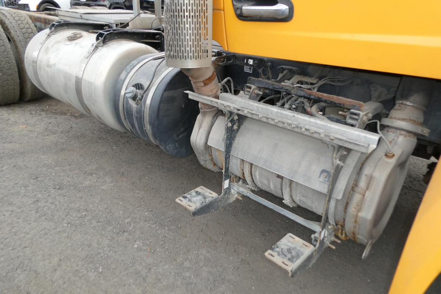 Conventional Daycab truck side showing fuel tanks and undercarriage components including exhaust stack and mounting brackets.