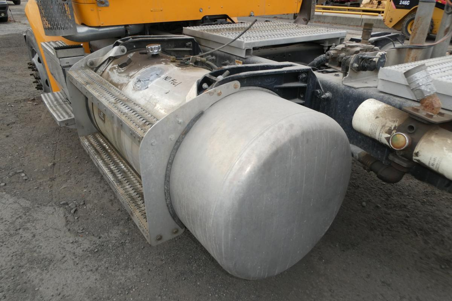 Tank on side of Peterbilt 567 truck showing cylindrical aluminum fuel or liquid tank and surrounding chassis components.