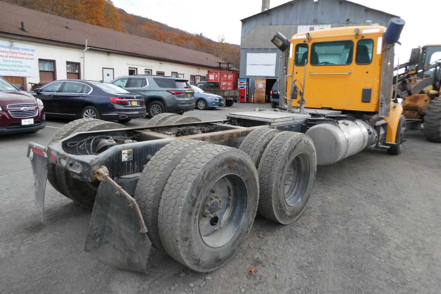 Peterbilt 567 truck chassis and rear wheels showing fifth wheel and tires in a yard.