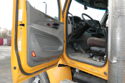 Peterbilt 567 cab interior and open door showing driver seat and dashboard area.