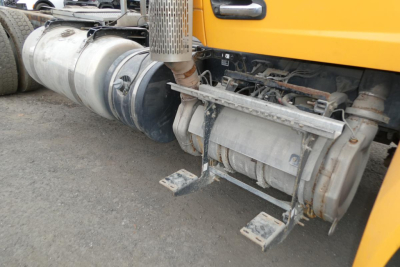 Conventional Daycab truck side showing fuel tanks and undercarriage components including exhaust stack and mounting brackets.