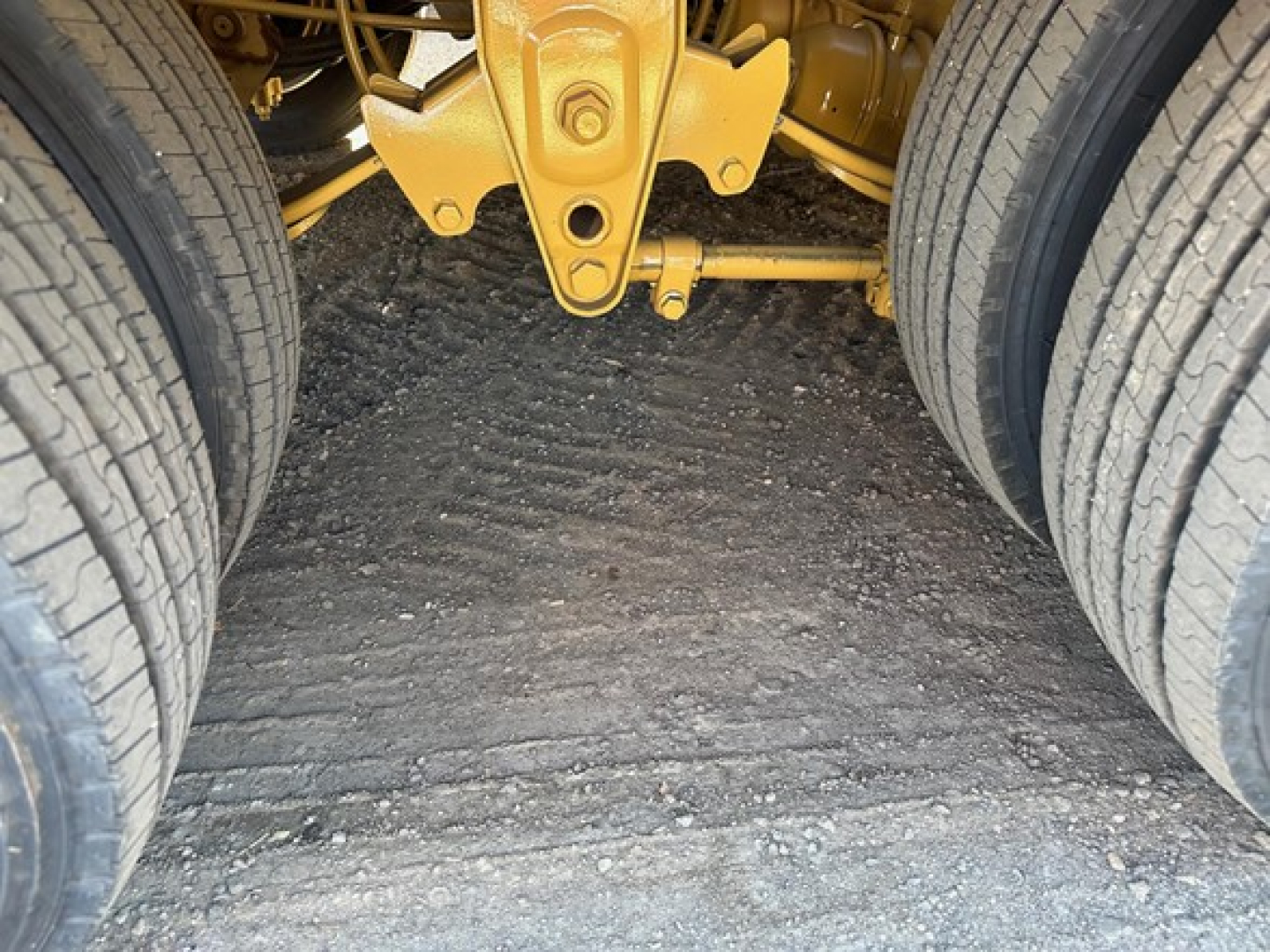 Trailer undercarriage showing leaf spring suspension and dual tires with yellow-painted frame in view, hydraulic air ramps not visible.