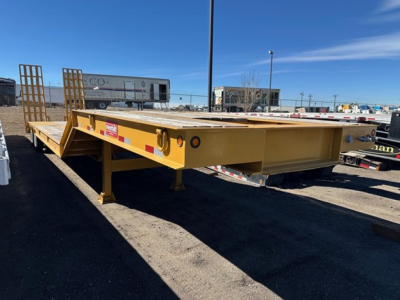 Equipment trailer with lowboy style, yellow-painted, flatbed with front ramps and side markers, showing sturdy frame and landing gear.