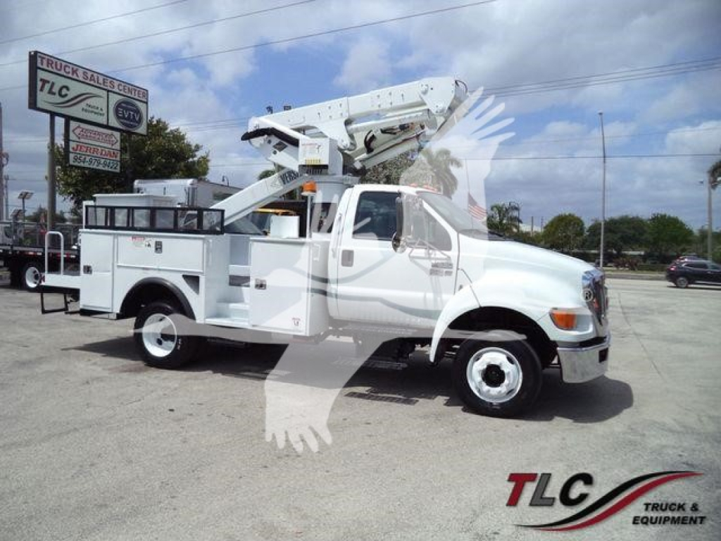 Versalift VST40i crane truck in serviceable condition, white utility truck with mounted aerial boom crane, side compartments, and stabilizers. TCG Truck Sales logo watermark.