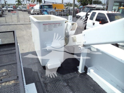 Versalift VST40i crane arm and control bucket on a truck bed, with white metal framework and warning labels on the bucket.