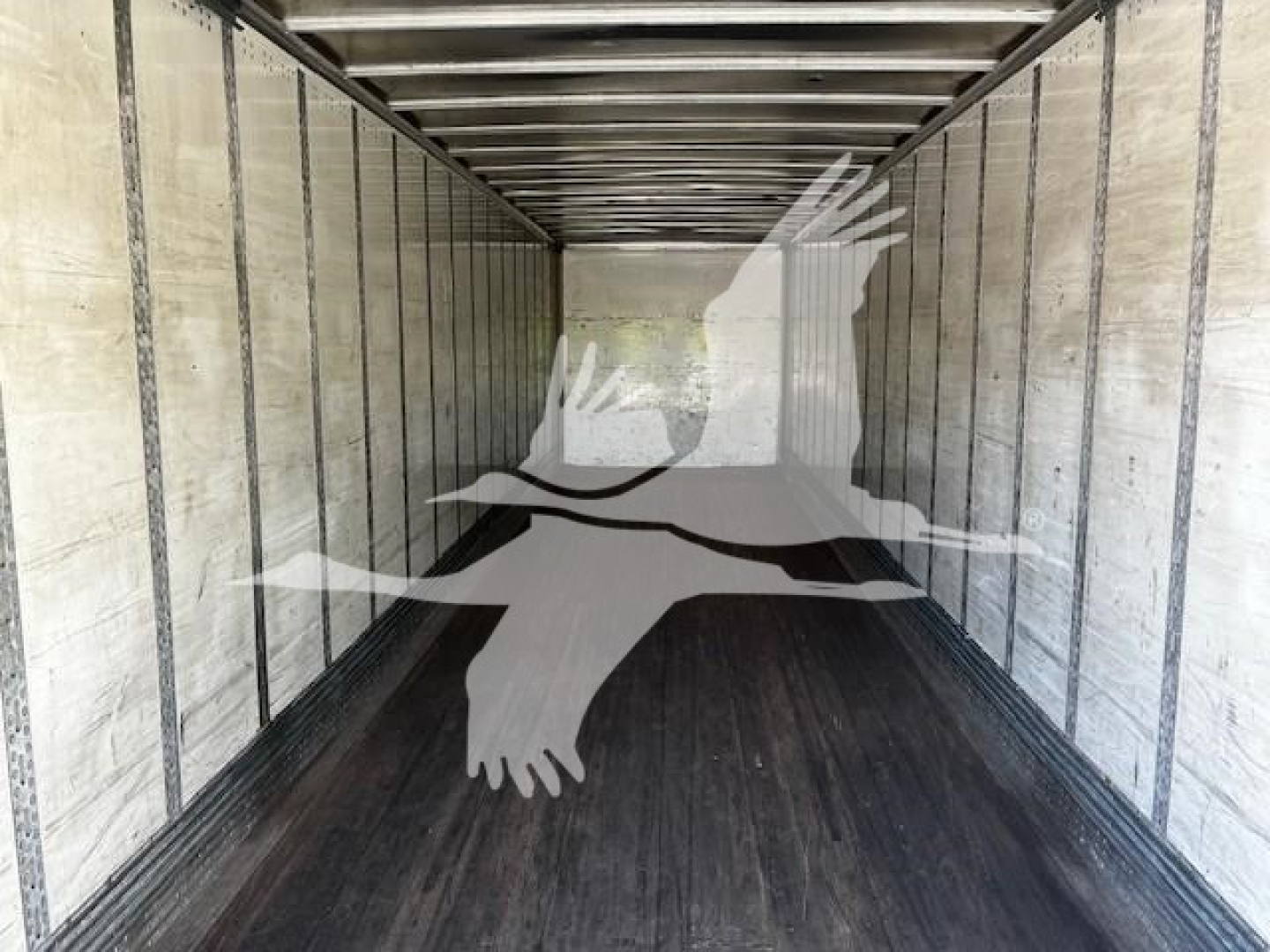 Trailer interior showing long empty cargo space with ribbed walls and wooden floor panels.