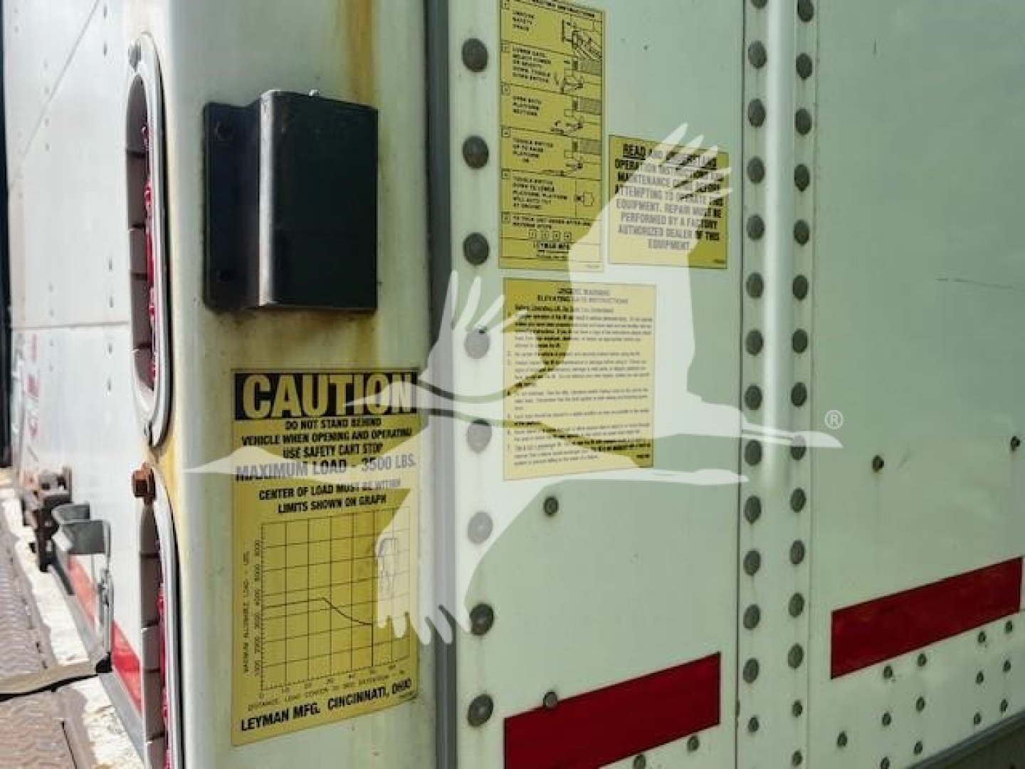 Trailer side showing yellow warning sticker and support bracket on green-painted body of a 2014 Wabash van trailer, with caution label and riveted panels.