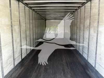 Trailer interior showing long empty cargo space with ribbed walls and wooden floor panels.