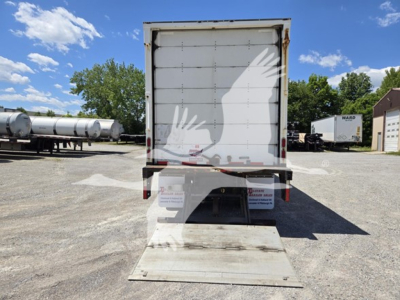 Rear view of a used 2014 Wabash van trailer with a lowered dock ramp, loading area, and rear doors closed; stock and VIN information visible but not legible in detail.