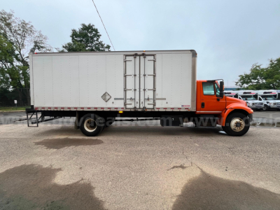 Truck side view showing box truck with orange cab and white cargo box, VIN and stock not visible, no text legible on door.