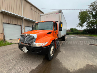 Truck in service orange cab with box body showing front grille and headlights, North American medium-duty truck.