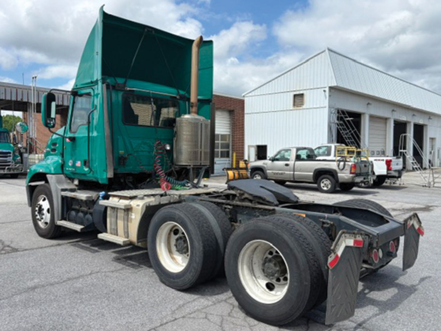 2015 Mack CXU613 truck tractor side rear view showing dual rear axles and sleeper cab with teal paint.