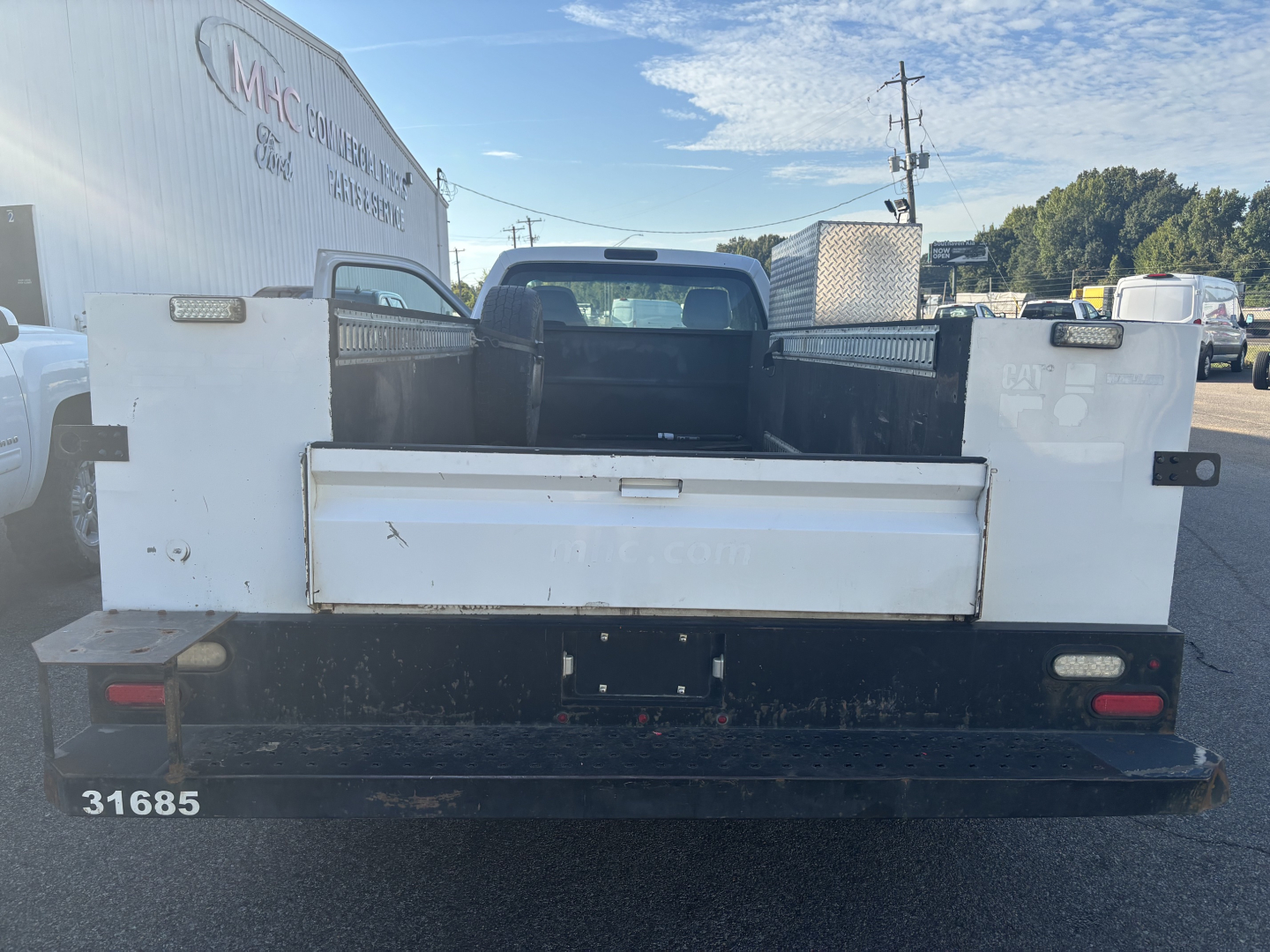 Back view of a white Ford F-350 cab and chassis pickup with cargo bed and tailgate, showing stock number 31685 and rear lights.