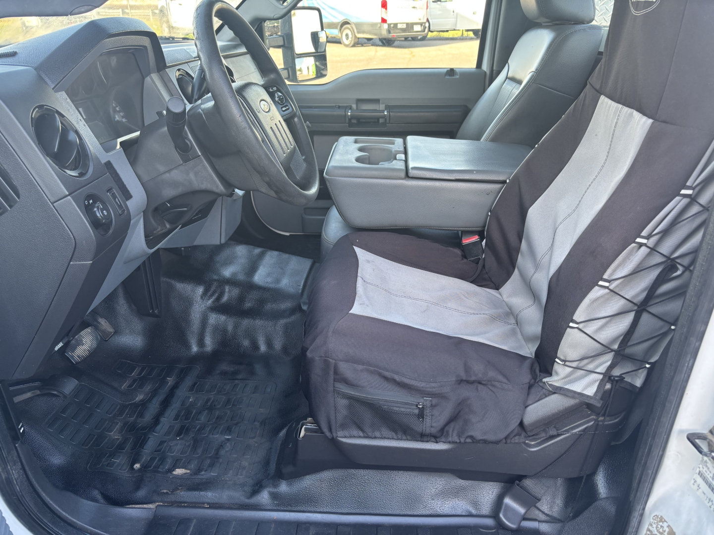 Ford F-350 cab and chassis interior showing driver's seat, steering wheel, center console armrest, and front passenger seat with two-tone fabric. Dashboard and floor mats visible.