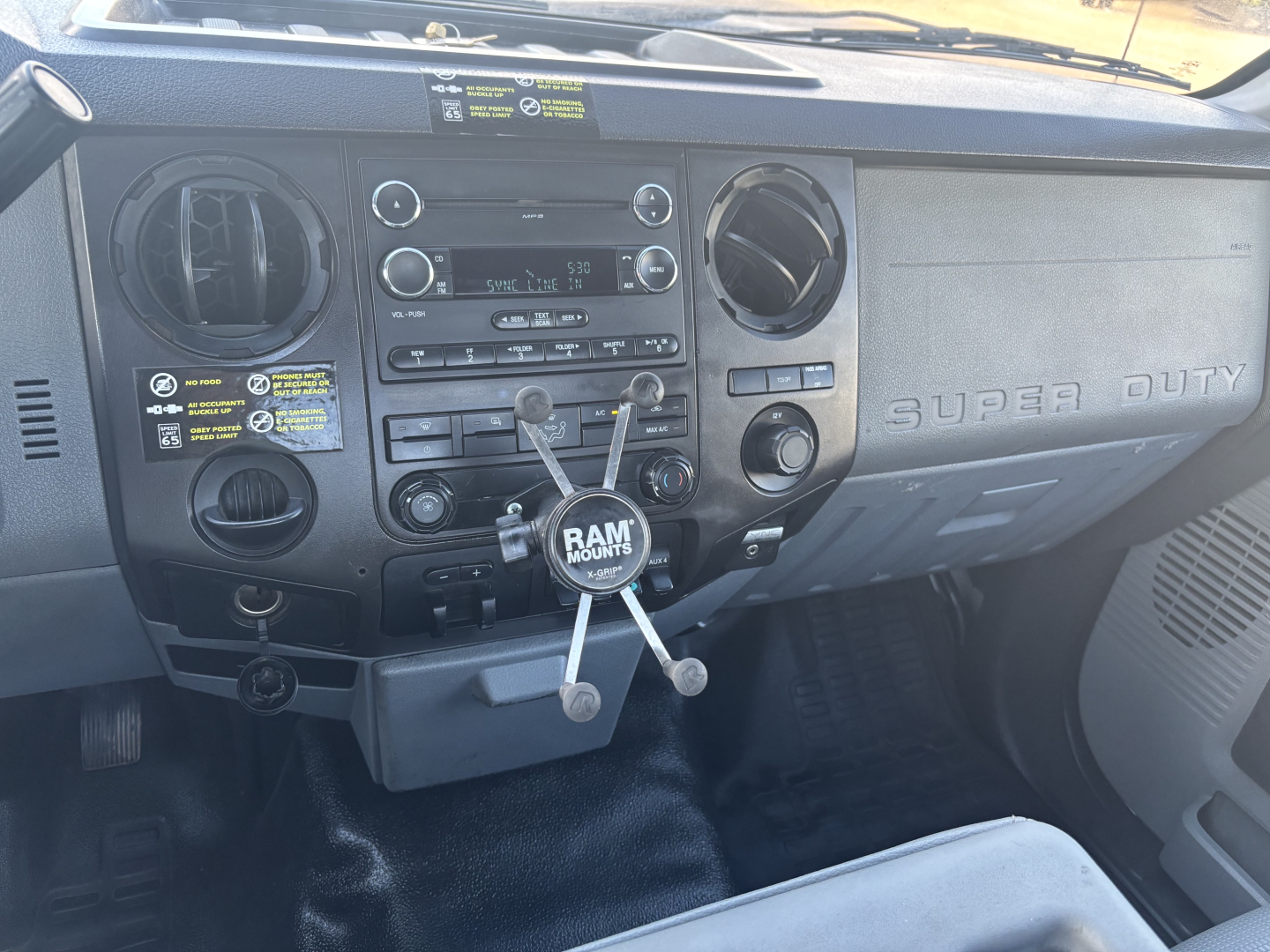 Dashboard of a 2015 Ford F-350 cab and chassis showing the radio, climate controls, and ram-mount with three arms.