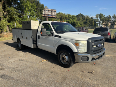 Ford F-350 cab and chassis utility truck in a parking lot, white with utility box and diamond-plate compartments.