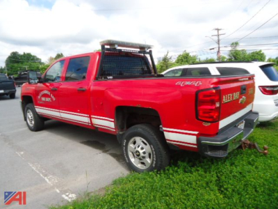 Chevrolet Silverado 2500HD crew cab pickup truck rear three-quarter view with red paint, white racing stripes, utility rack, and bumper hitch.