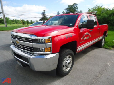 Chevrolet Silverado 2500HD crew cab pickup truck in red with white lettering on the door showing a utility company's branding, 4x4 badge visible, in a parking lot.