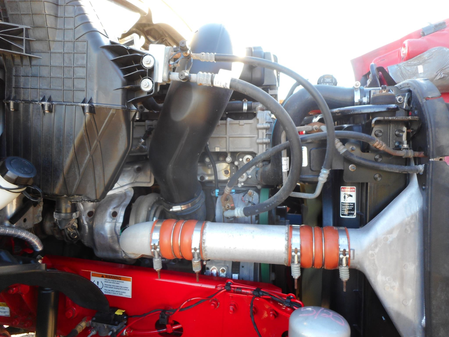 Engine bay of a Freightliner Cascadia showing hoses, intercooler piping, and auxiliary components.