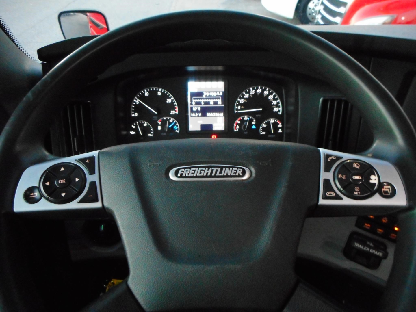 Freightliner Cascadia interior cockpit with steering wheel and instrument cluster visible.
