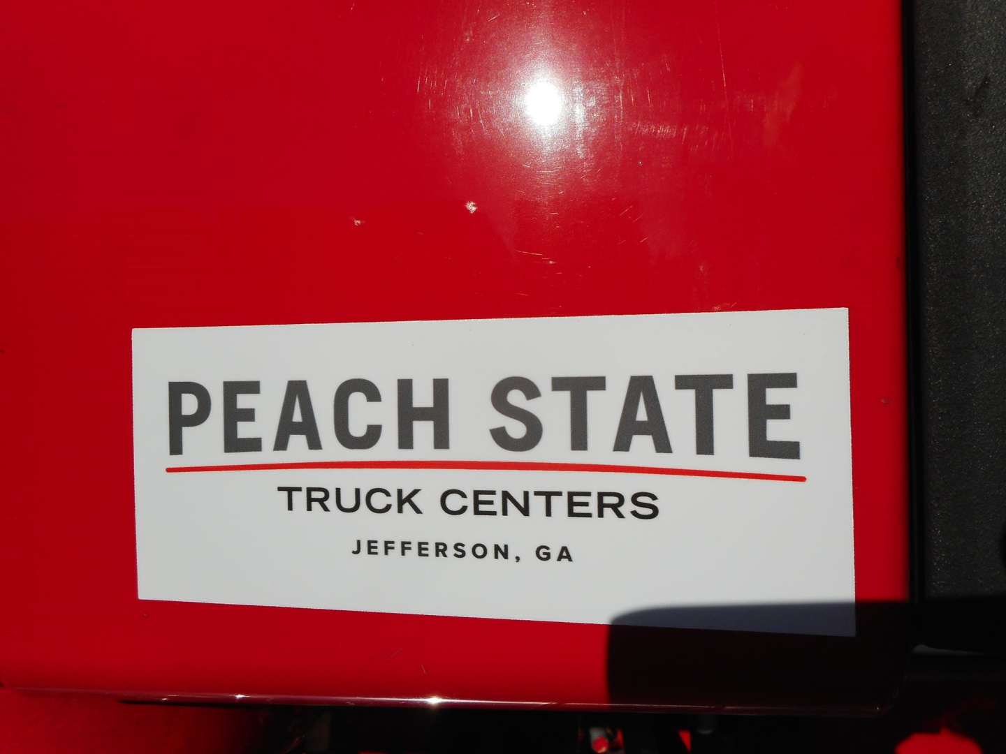 Peach State Truck Centers sticker on a red surface reading PEACH STATE TRUCK CENTERS JEFFERSON, GA