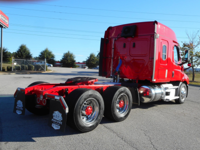 Truck chassis in a red Freightliner Cascadia 116 tractor with three rear axles and chrome fuel tanks, showing red cab and black tires.