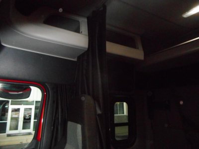 Cab interior of a 2020 Freightliner Cascadia sleeper showing overhead storage and window.