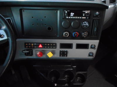 Dashboard and center console of a Freightliner Cascadia truck with climate controls, radio, and various switches visible.