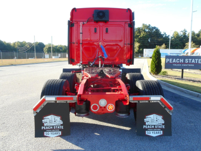 Rear view of a red Freightliner Cascadia tractor showing chassis and rear fenders with Peach State Truck Centers mudflaps and a blue strap.